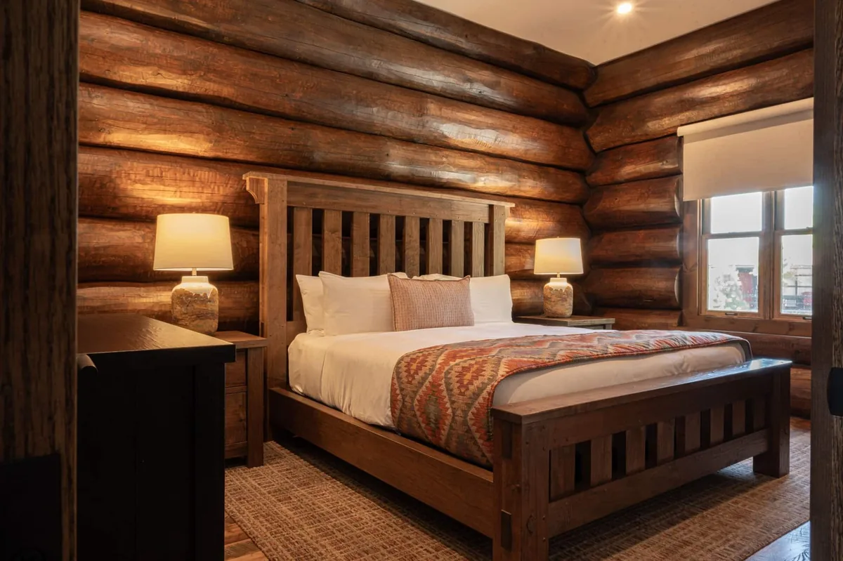 Log-cabin bedroom with timber walls and warm bedside lighting at Killarney Mountain Lodge
