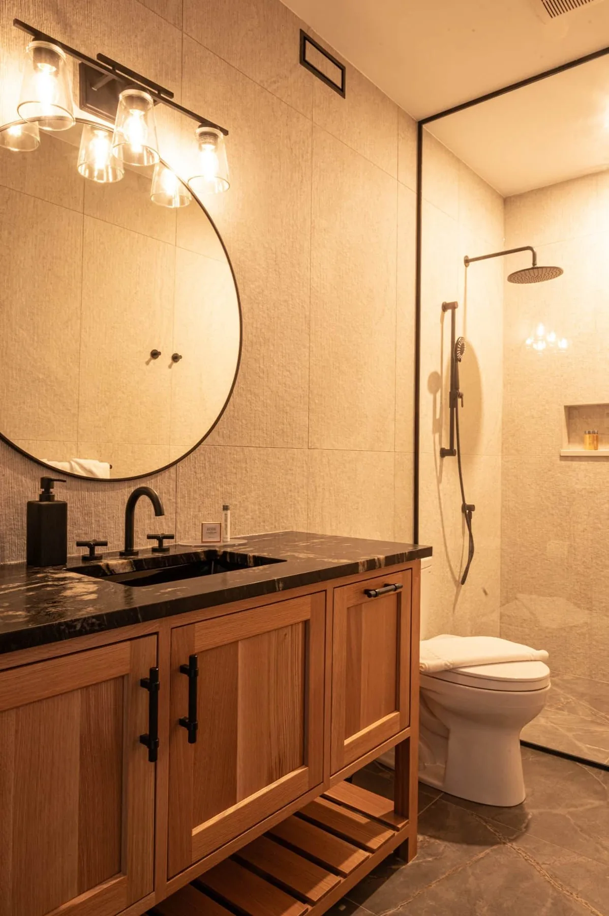 Cabin bathroom with a round mirror, wood vanity and shower at Killarney Mountain Lodge