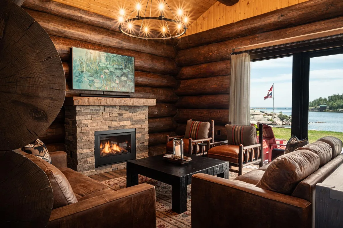 Log-cabin living room with a stone fireplace and water-facing doors at Killarney Mountain Lodge