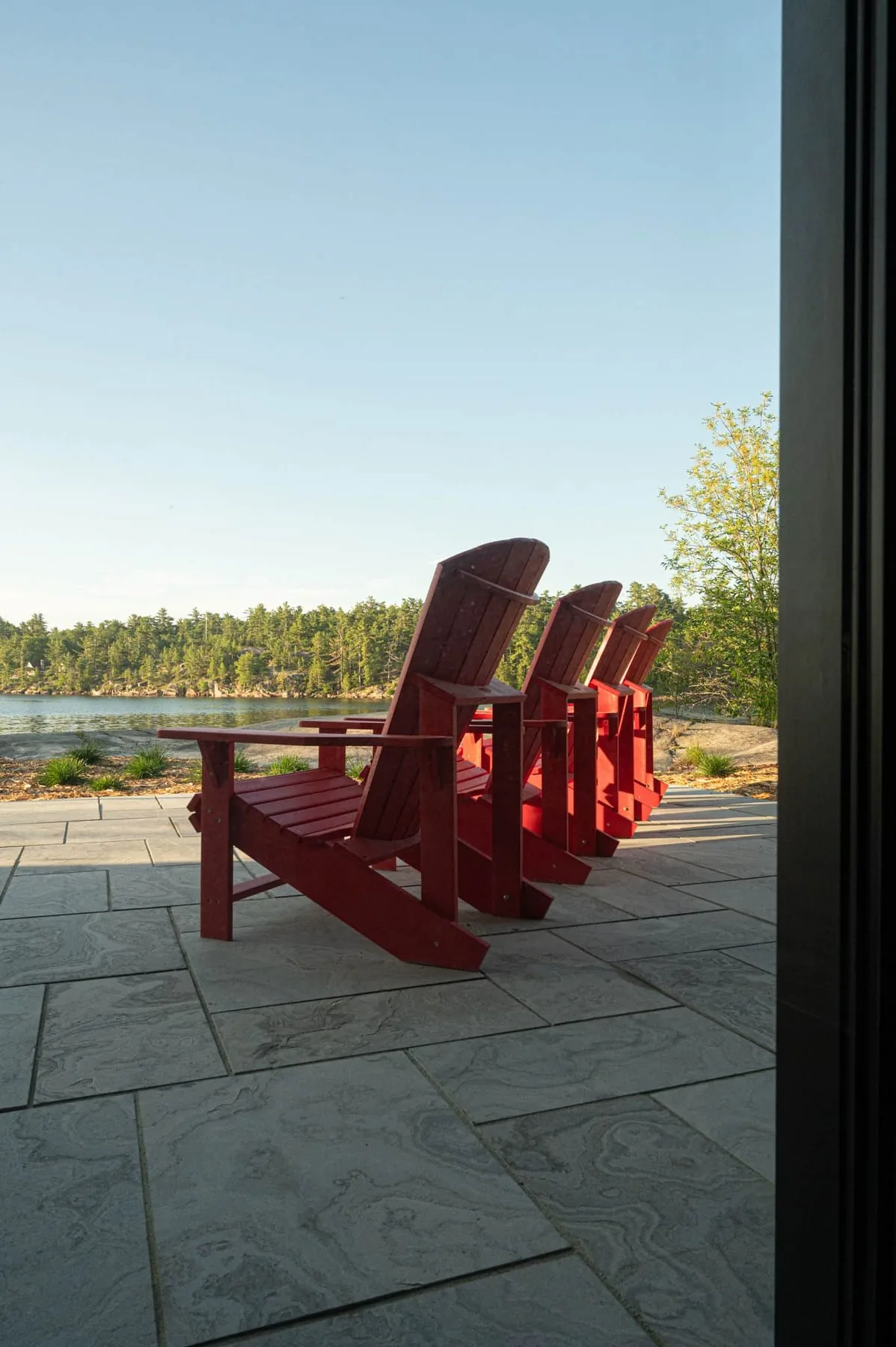 Red Adirondack chairs on a stone terrace in the green season at Killarney Mountain Lodge