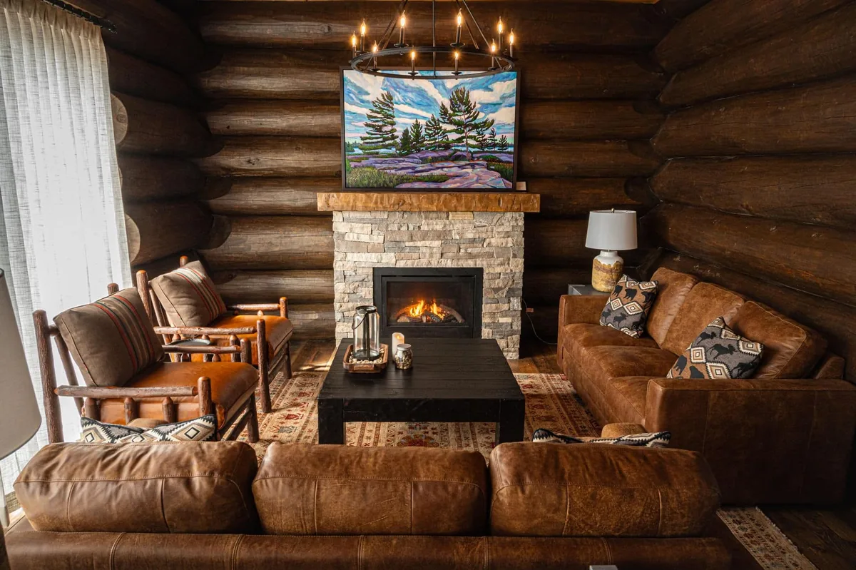 Leather seating around a stone fireplace in a log cabin at Killarney Mountain Lodge