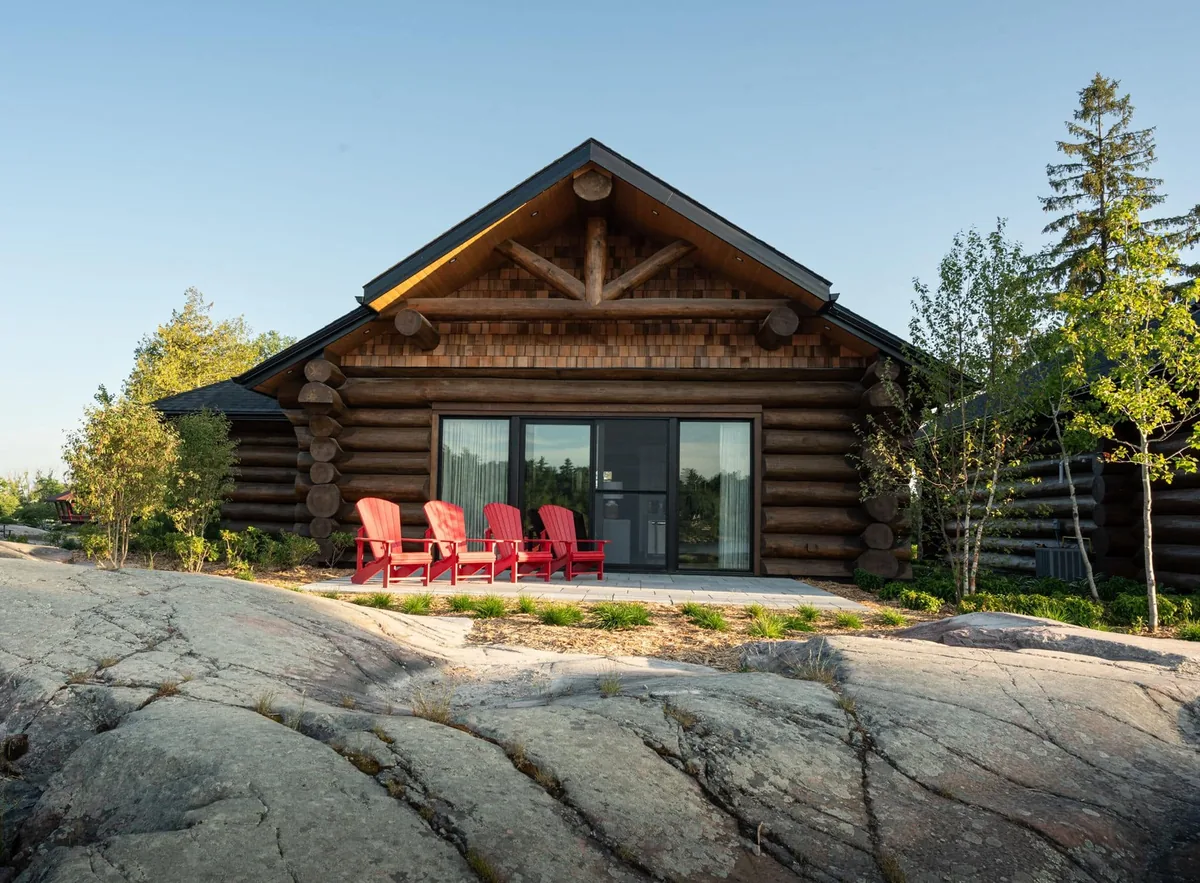 Waterfront log cabin exterior and stone terrace in the green season at Killarney Mountain Lodge