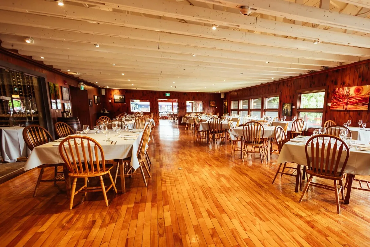 The Main Dining Room with set tables, wood floors and channel-facing windows.